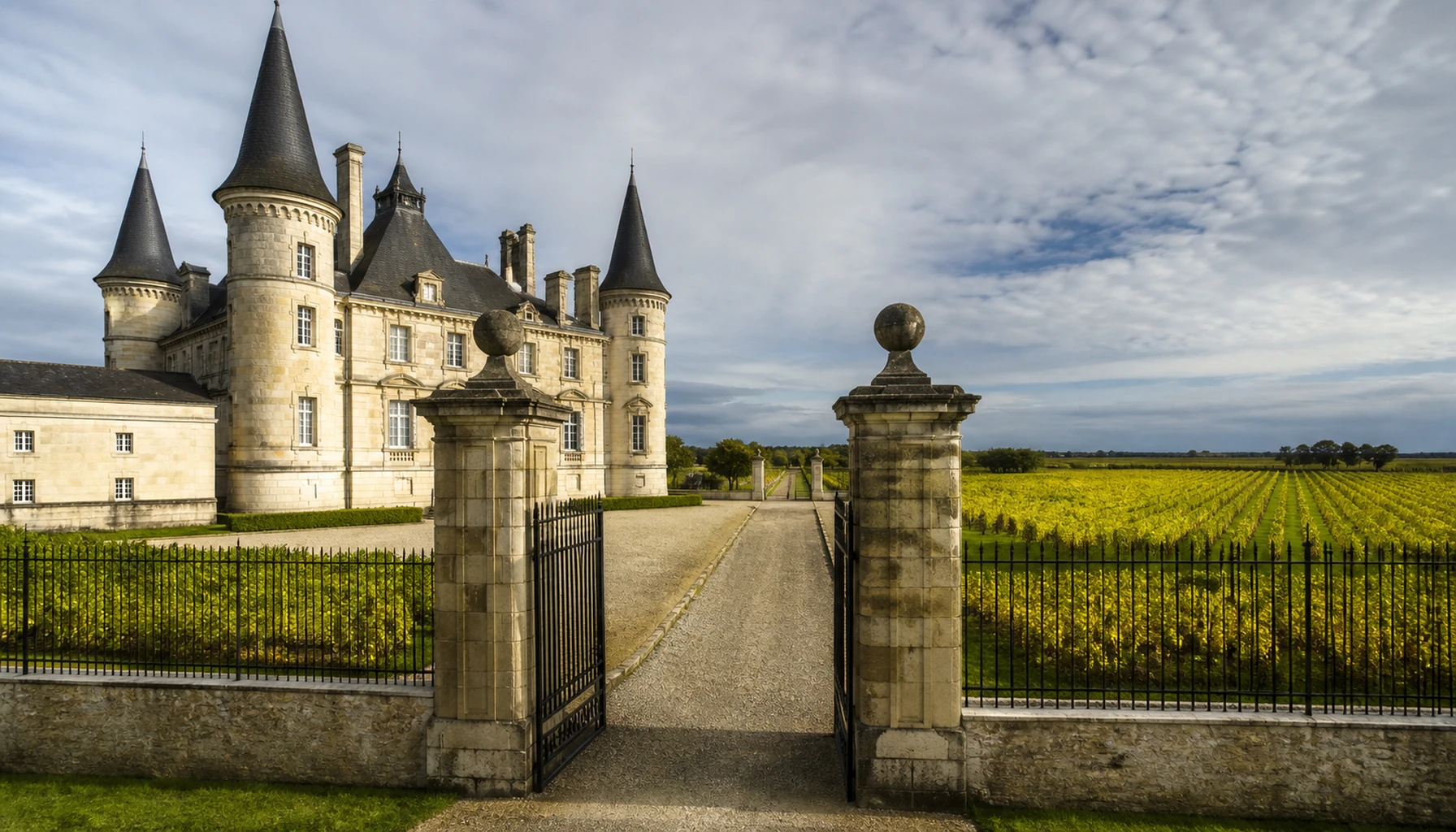 Gravel rows before a stone château on the Bordeaux left bank — the country that built the pair